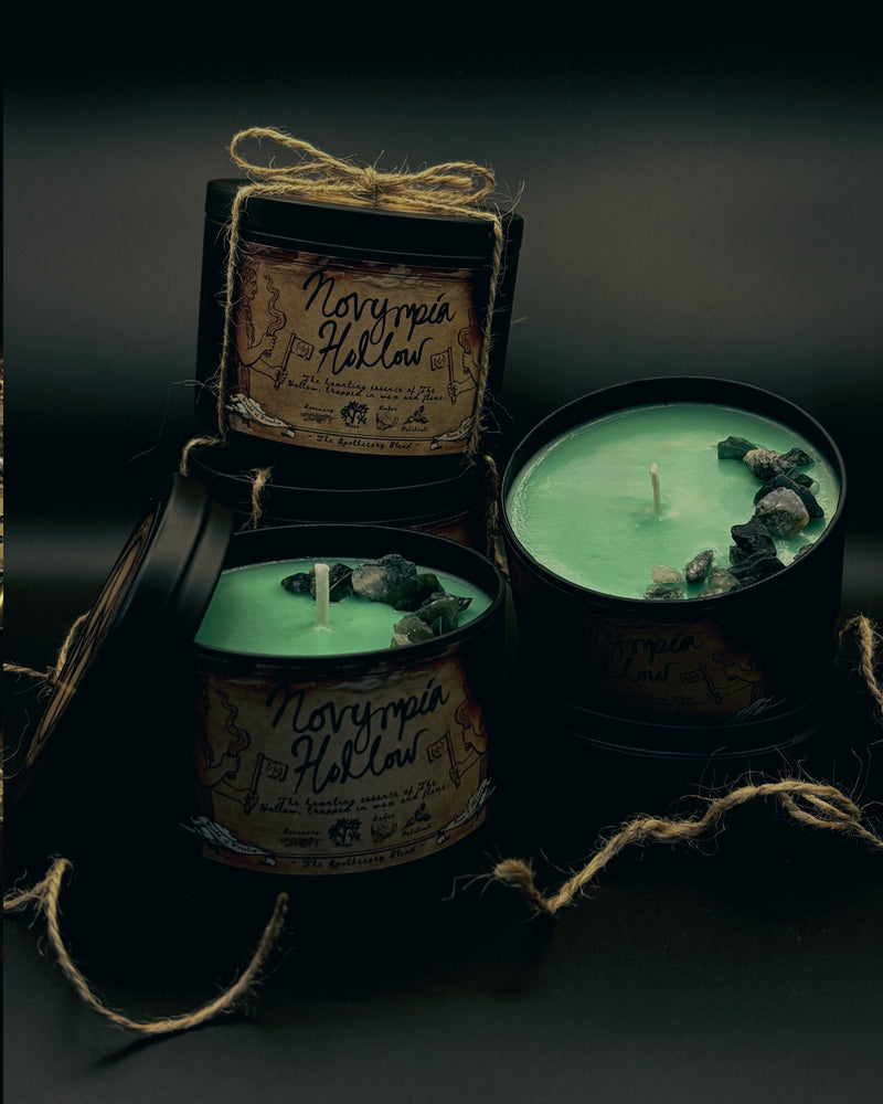 Four candles in black tins with decorative labels on a dark background